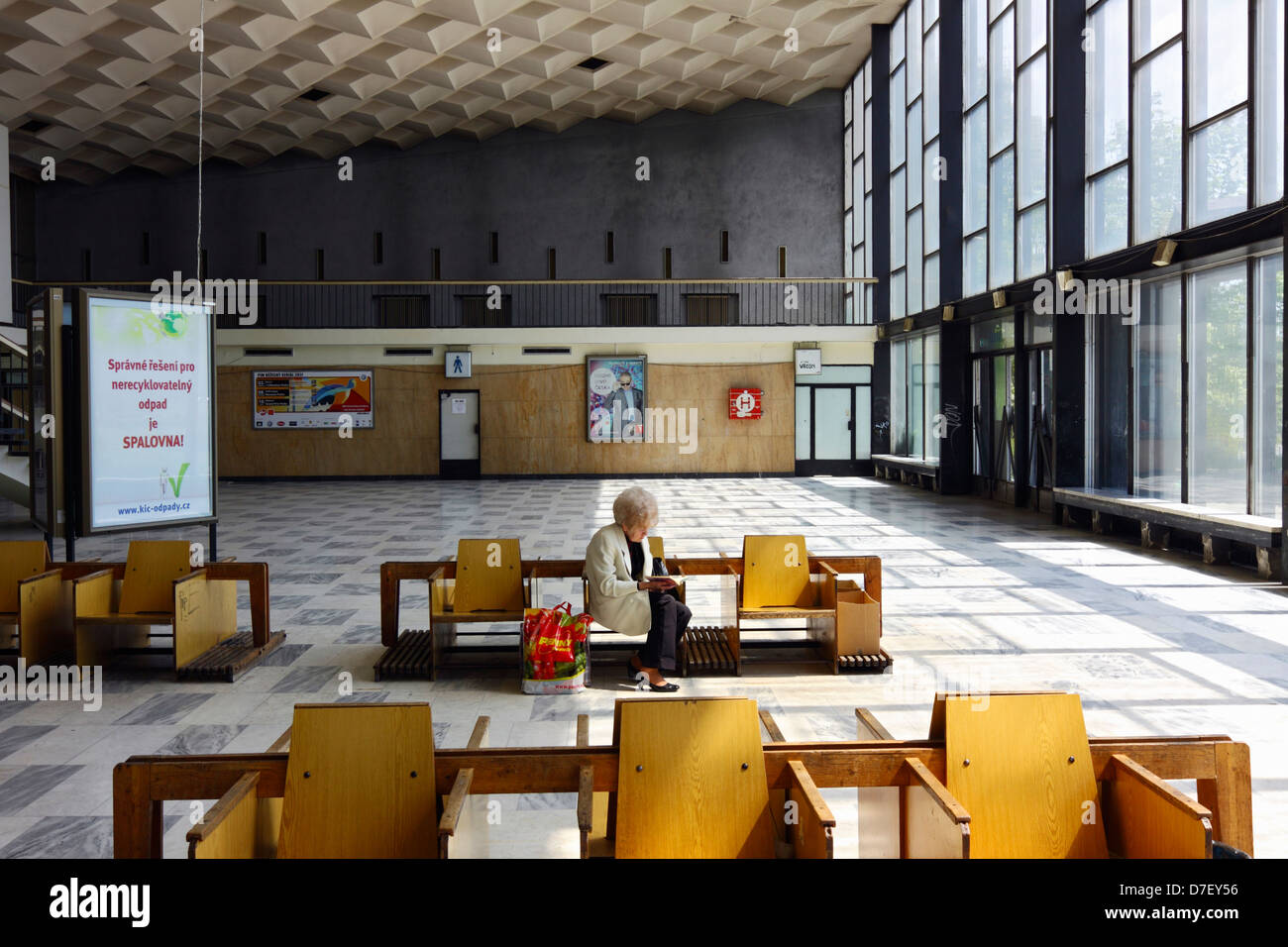 A lonely old woman reading in the hall of Havirov train station Czech Republic Stock Photo