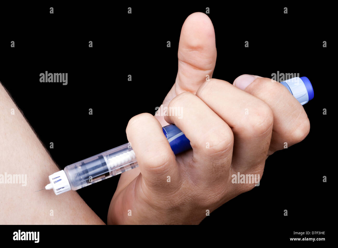 A macro shot hand holding syringe full insulin about to penetrate arm young adult man Diabetes. Isolated on black background. Stock Photo