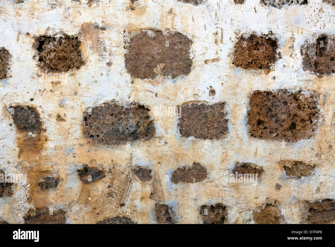 Close up of an ancient stone wall covered with (what used to be) white plaster. Stock Photo