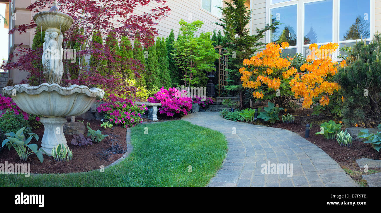 Frontyard Landscaping with Water Fountain and Brick Pavers Path with Azalea Flowers in Bloom Stock Photo