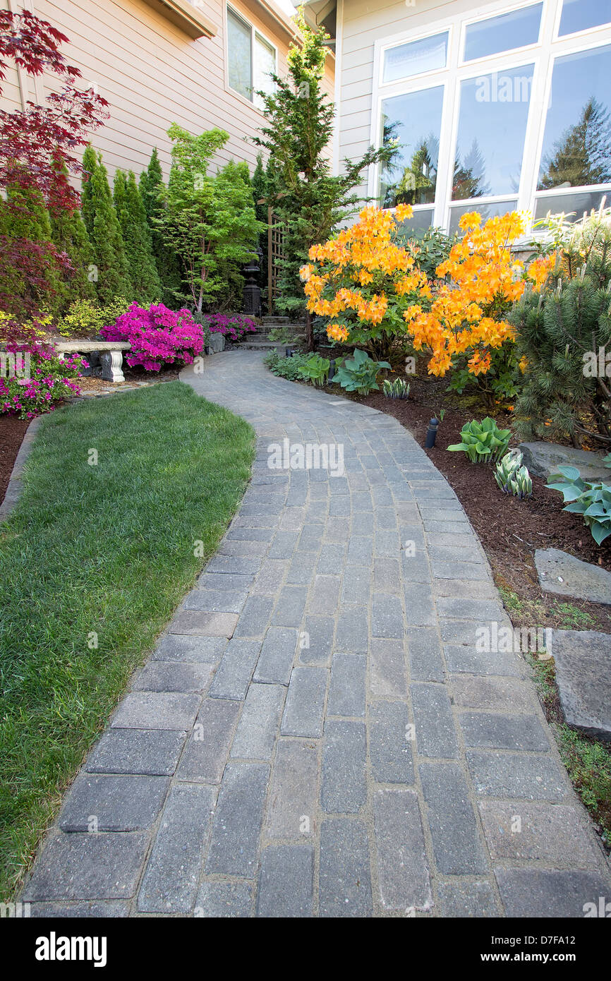 Garden Brick Paver Path Walkway with Green Grass Lawn and Landscaping Plants Stock Photo