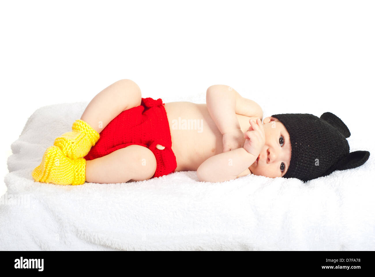 Beautiful newborn baby lying down on fluffy blanket dressed in knitted costume isolated on white background Stock Photo