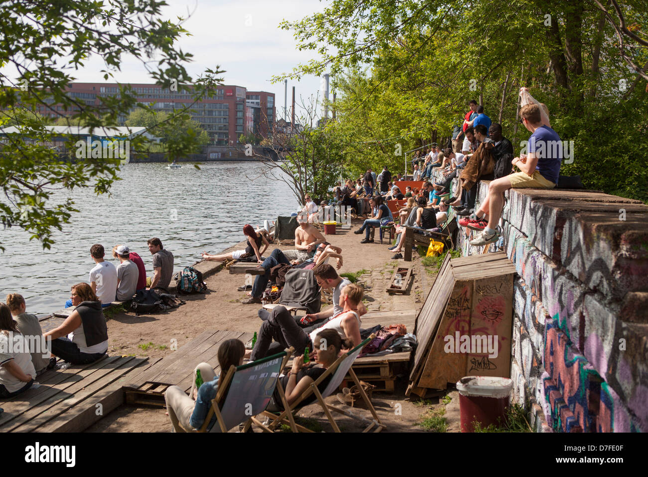Young german people sitting in the sun at the river Spree at Yaam, a meeting place and restaurant at Friedrichshain Berlin Stock Photo