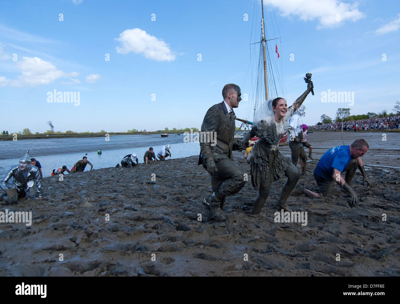 A bride holding a mud covered rose. The Maldon Mud Race is an annual event, which sees competitors race across the mud . Stock Photo