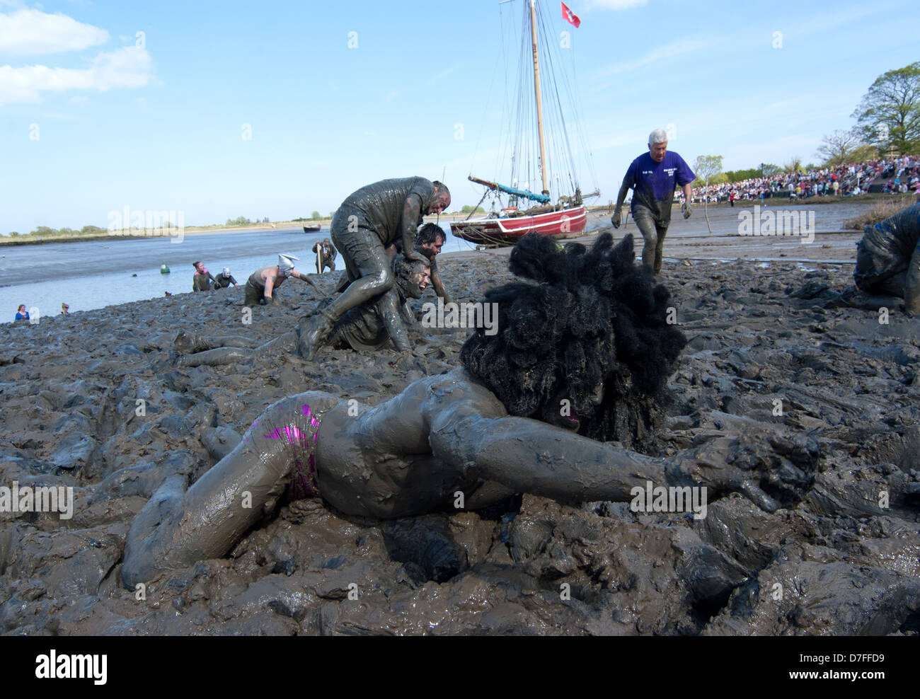 A runner is trapped in the mud and requests a hand in finishing the race. The Maldon Mud Race is an annual event. Stock Photo