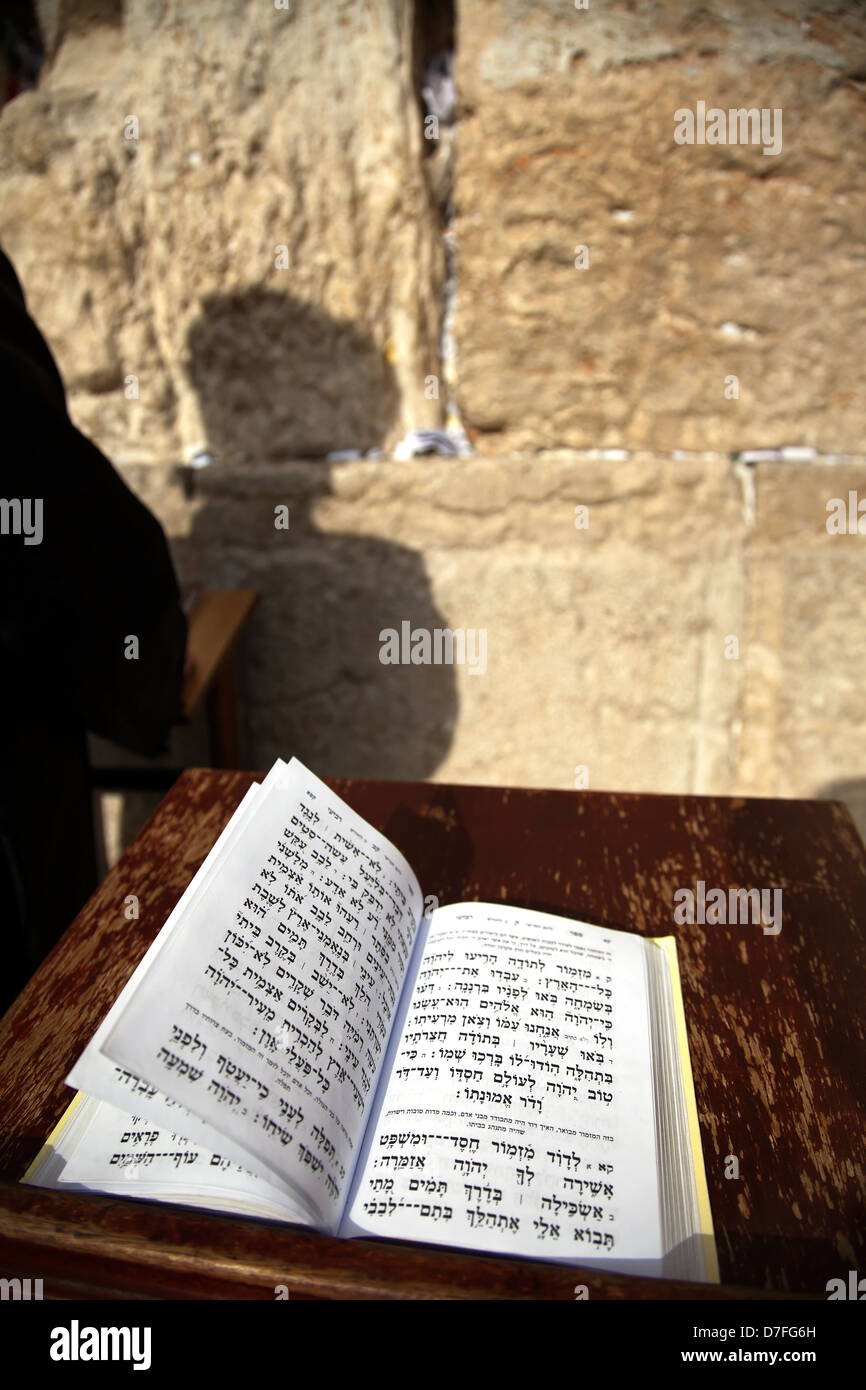 The biblical Book Psalms opened on one pages morning prayer resting on pedistal . There's also Jewish orthodox man infront Stock Photo