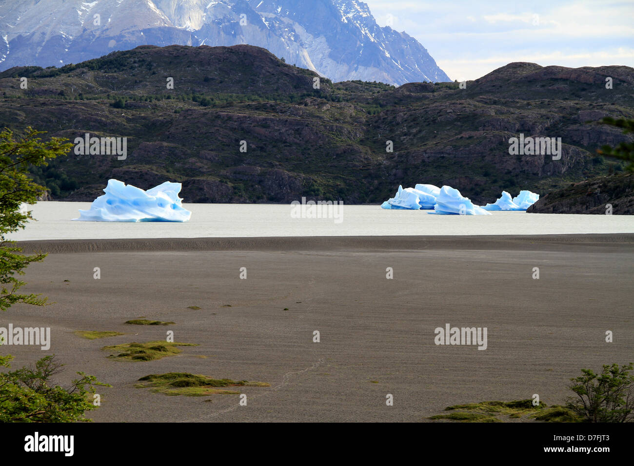 The remains glacier in mode small ice islands in middle lake. In foreground - flat land is dry lake.Shot in Patagonia South Stock Photo