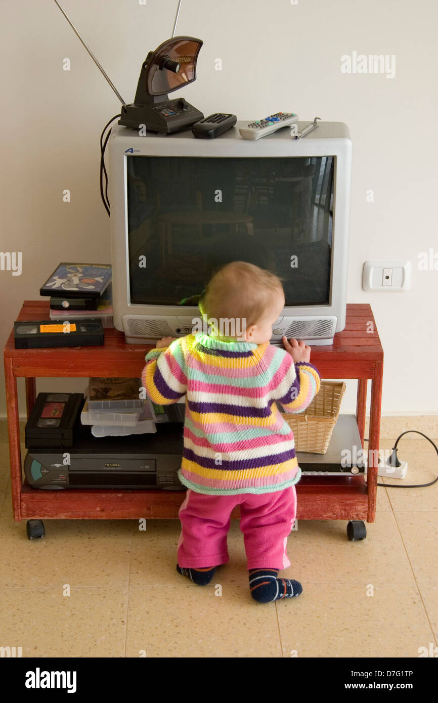 one year old baby barely standing in front of TV Stock Photo