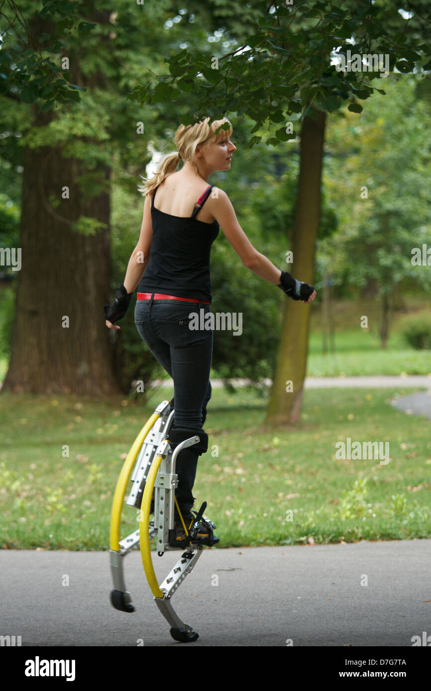 Young woman wearing jumping stilts exercising in the park Stock Photo Alamy