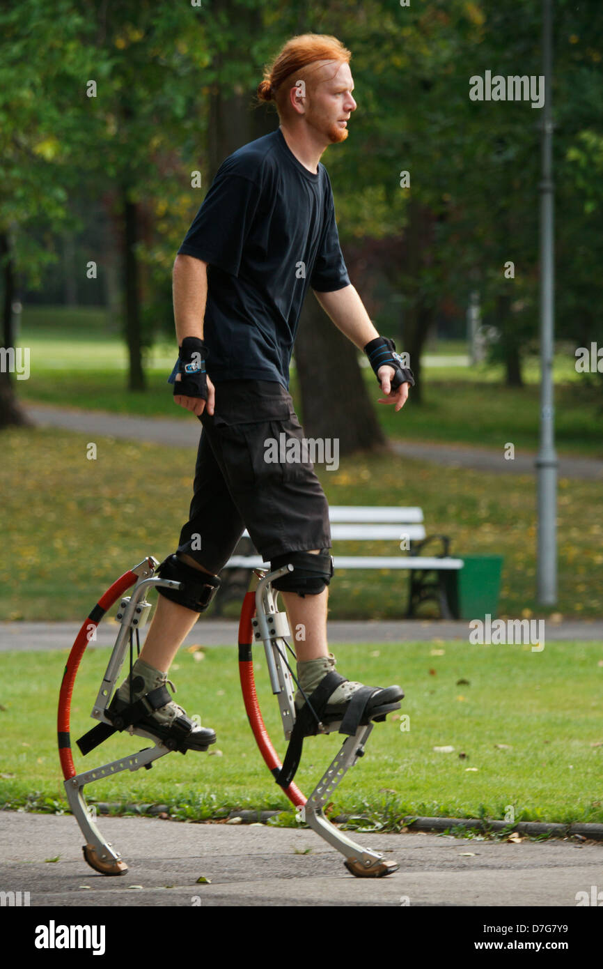 Young man wearing jumping stilts exercising in the park Stock Photo Alamy