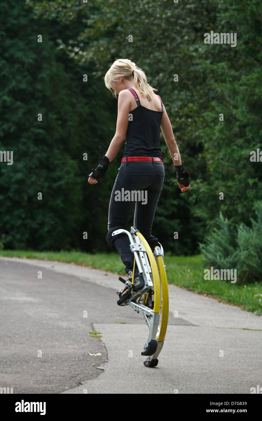Young woman wearing jumping stilts exercising in the park Stock Photo