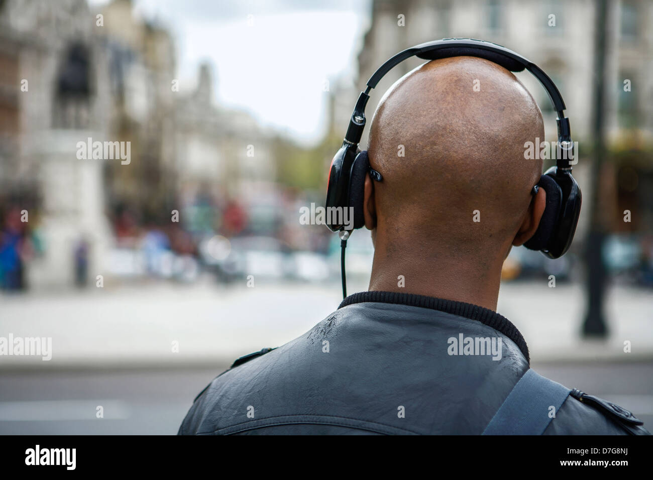 From Trafalgar Square, London UK, a tourist looks down White Hall and takes in the view - man wearing head phones. Stock Photo
