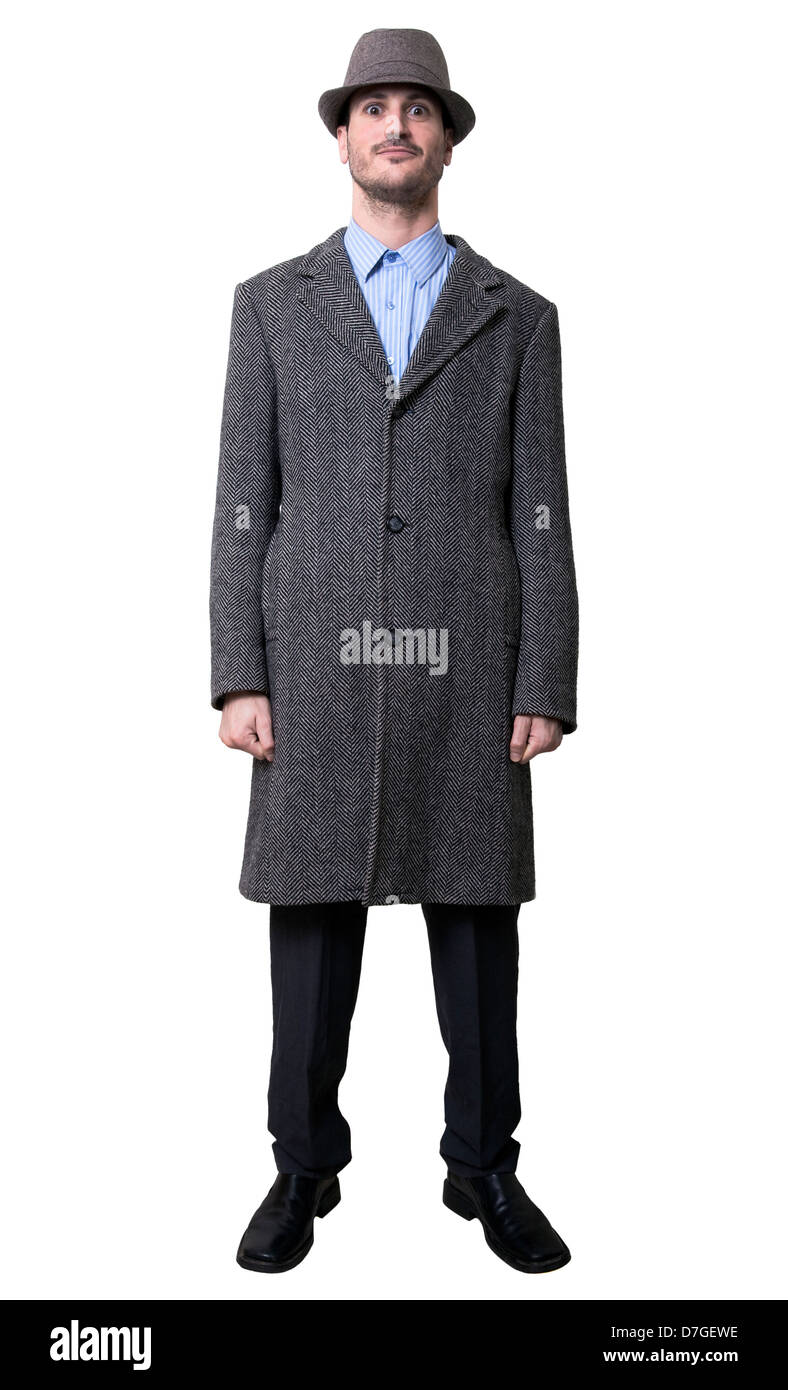 A young adult male wearing an overcoat matching hat smiling staring in an awkward manner to camera. Isolated on white Stock Photo