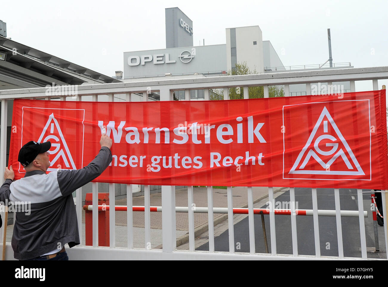 Eisenach, Germany. 7th May, 2013. A union member attaches a warning strike banner to the gate at the Opel plant in Eisenach, Germany, 07 May 2013. The IG Metall union called for warning strikes to emphasize their wage demands. Photo: BERND SETTNIK/dpa/Alamy Live News Stock Photo