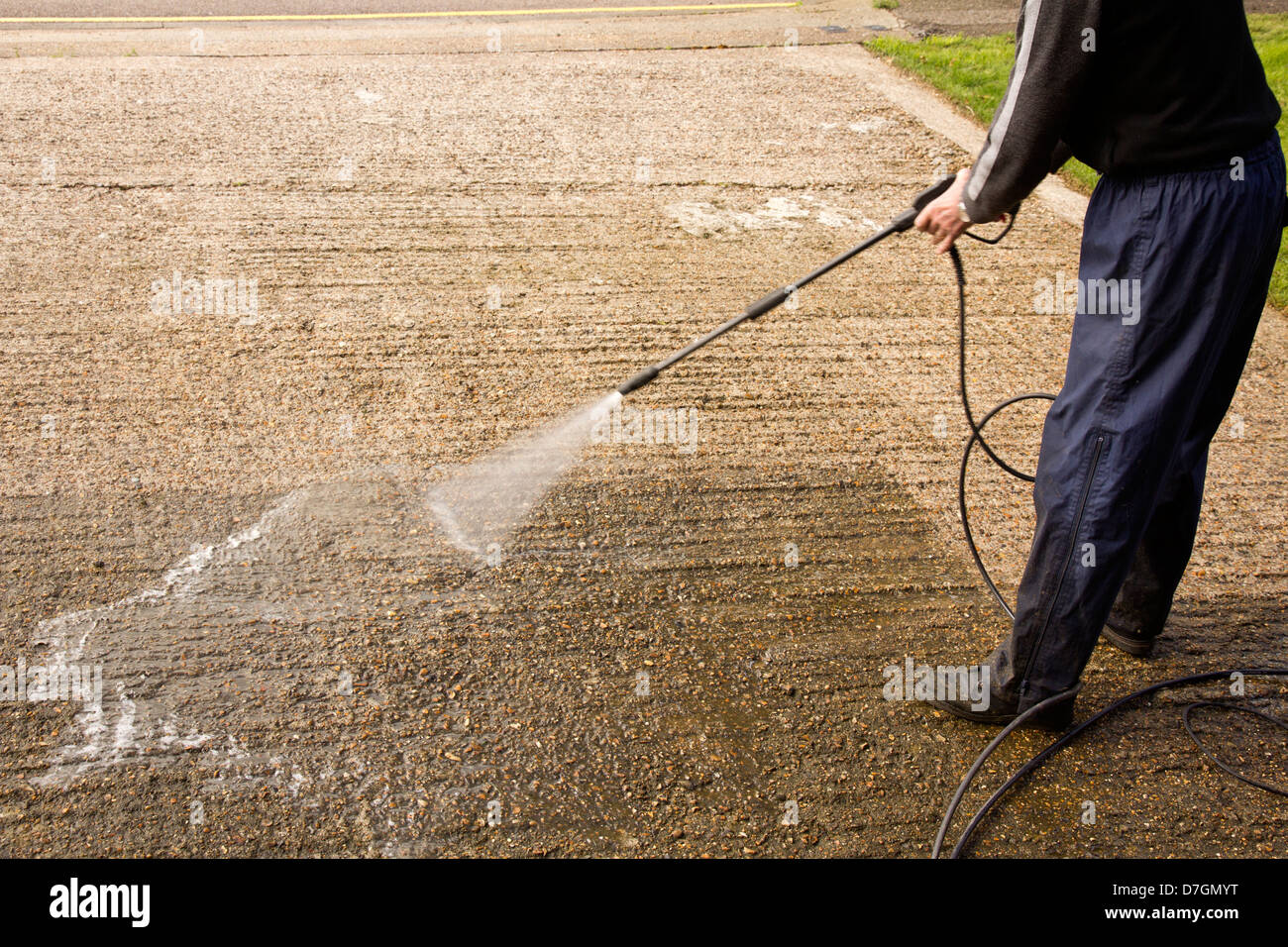 Man pressure washing a concrete driveway. Stock Photo
