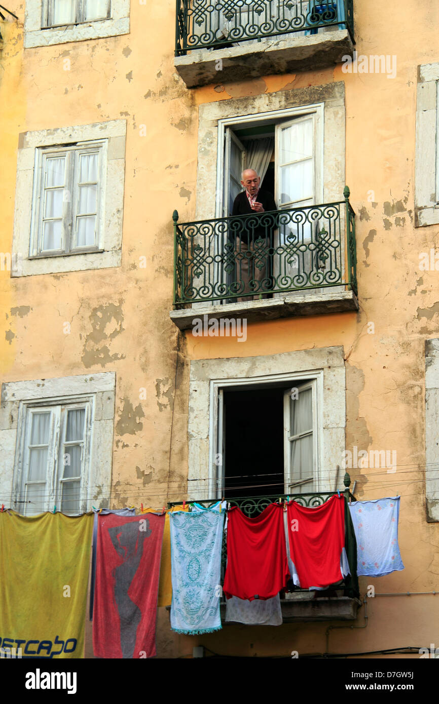 Washing hanging outside a building, with a man looking out from his balcony, Old Town, Lisbon, Portugal Stock Photo