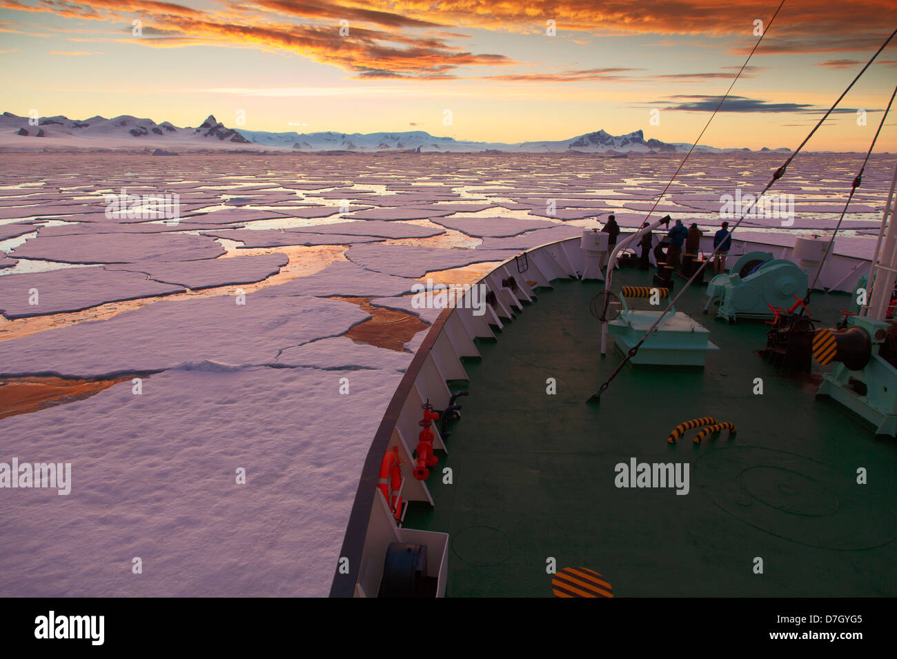 Icebreaker Ortelius moving through ice at sunset / sunrise as we travel below the Antarctic Circle, Antarctica.  Stock Photo