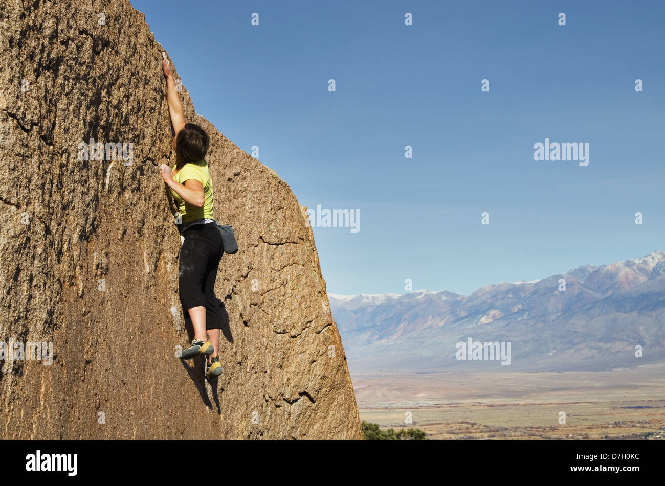 a woman rock climber makes a big reach for the top Stock Photo