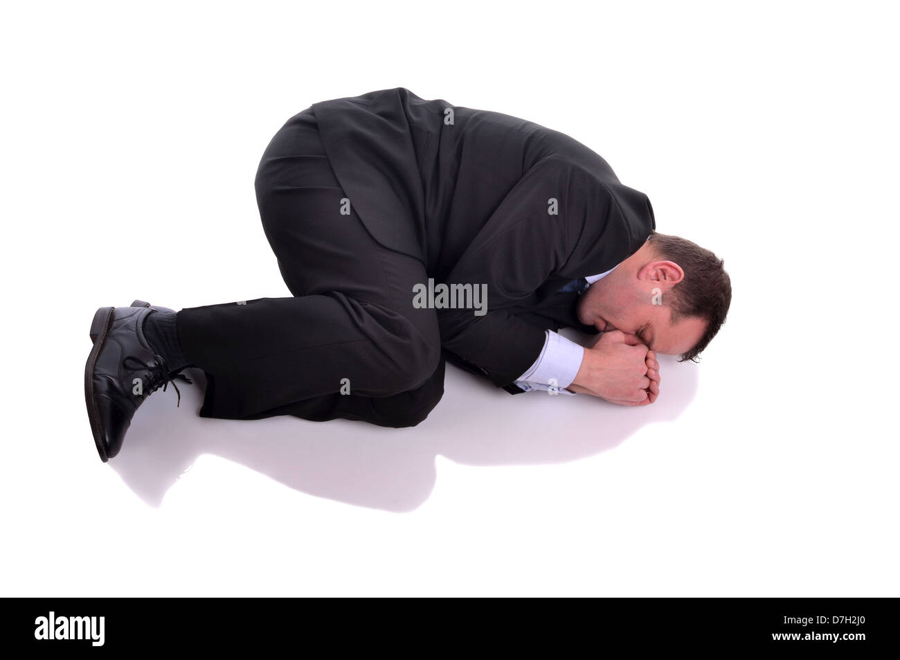 Businessman laying down in fetal position. Image is isolated on white Stock Photo