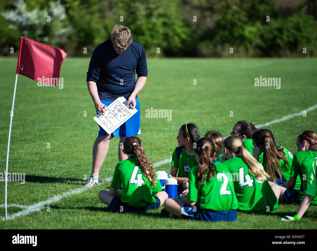 Coach reviews game plan during youth girls soccer match. Stock Photo