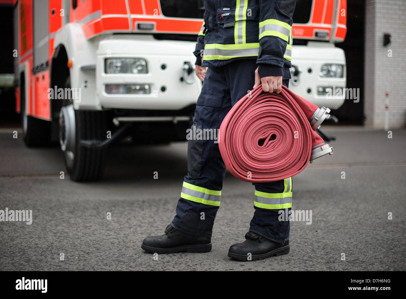 A firefighter carries a hose. Photo: Robert Schlesinger Stock Photo - Alamy