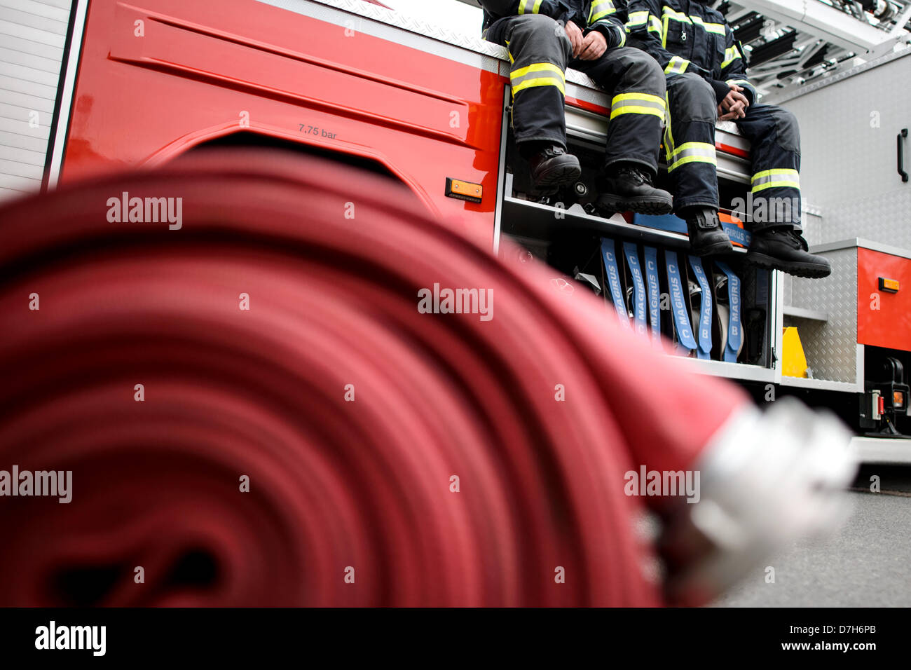 Two firefighters sit on a fire truck. Photo: Robert Schlesinger Stock Photo