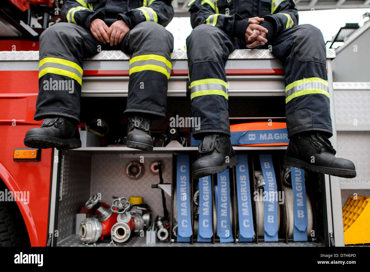 Two firefighters sit on a fire truck. Photo: Robert Schlesinger Stock Photo