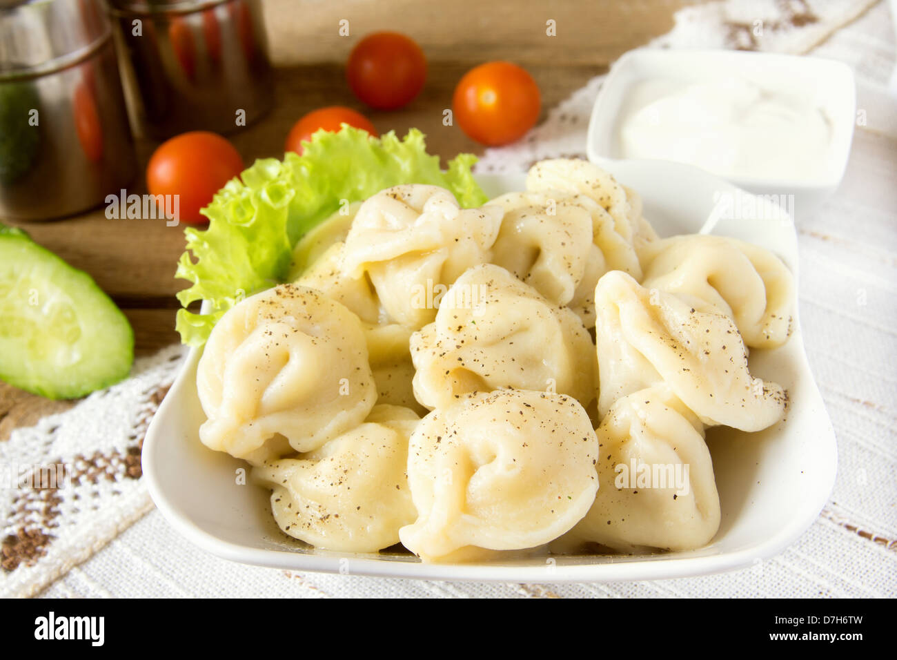 Meat dumplings (russian pelmeni) with pepper, vegetables and sour cream in bowl close up Stock Photo