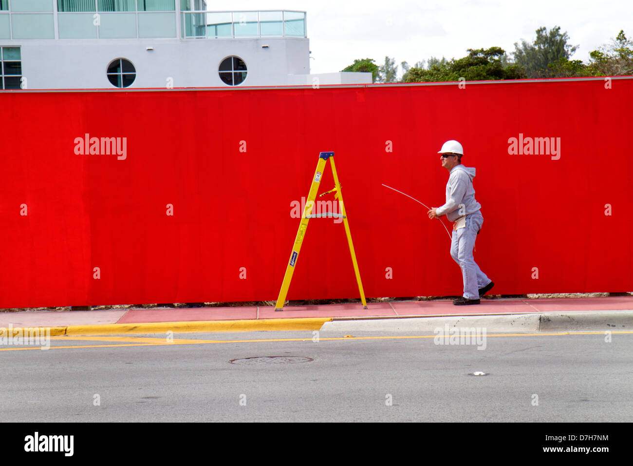 Miami Beach Florida,Collins Avenue,red,wall,yellow,ladder,under new construction site building builder,worker,workers,man men male adult adults,hard h Stock Photo