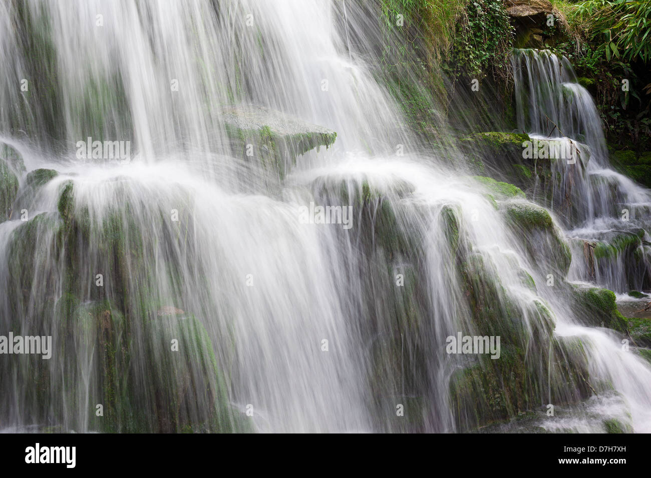 Water cascading over mossy rocks with long exposure blur Stock Photo