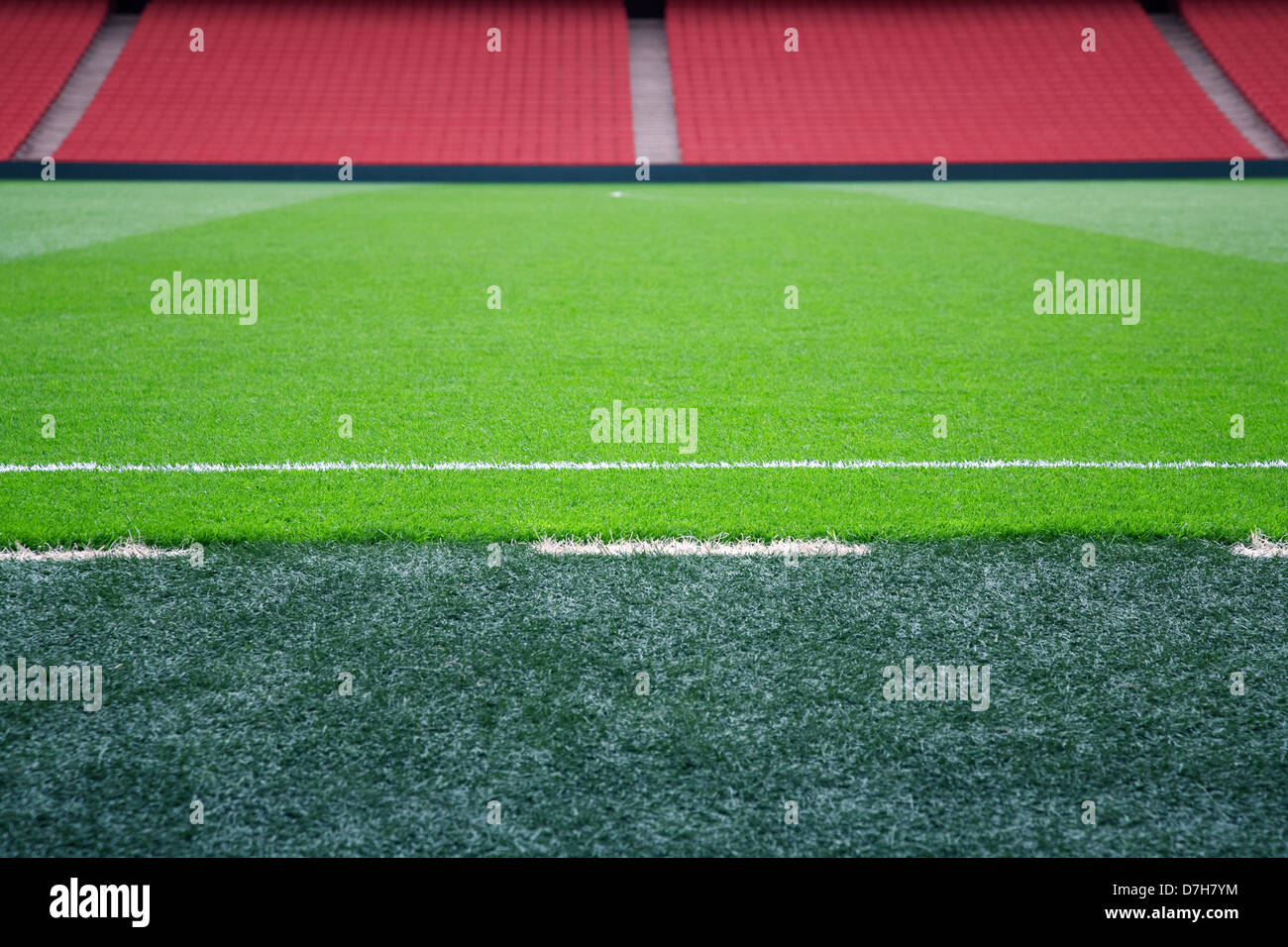 Empty football pitch with red seating, selective focus on touchline. Stock Photo