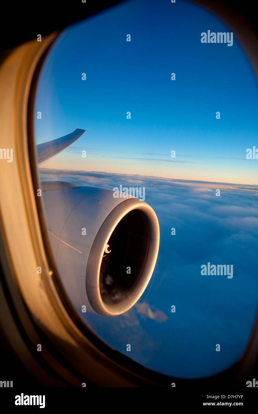 Passenger view through the window of a jet plane showing sky, clouds, jet engine and wing. Stock Photo