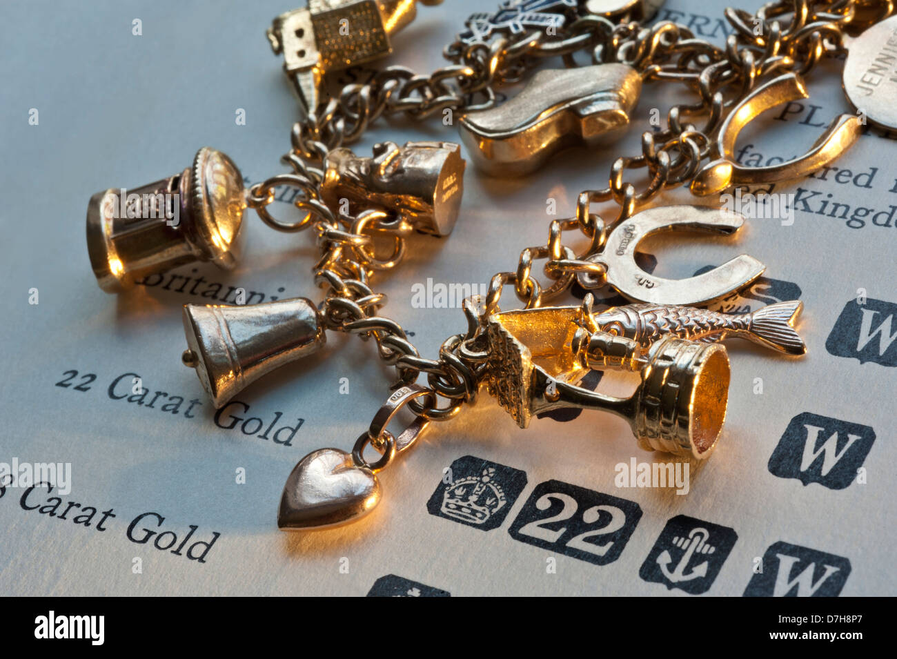 1960's gold charm bracelet on page of gold purity and hallmarks reference book Stock Photo