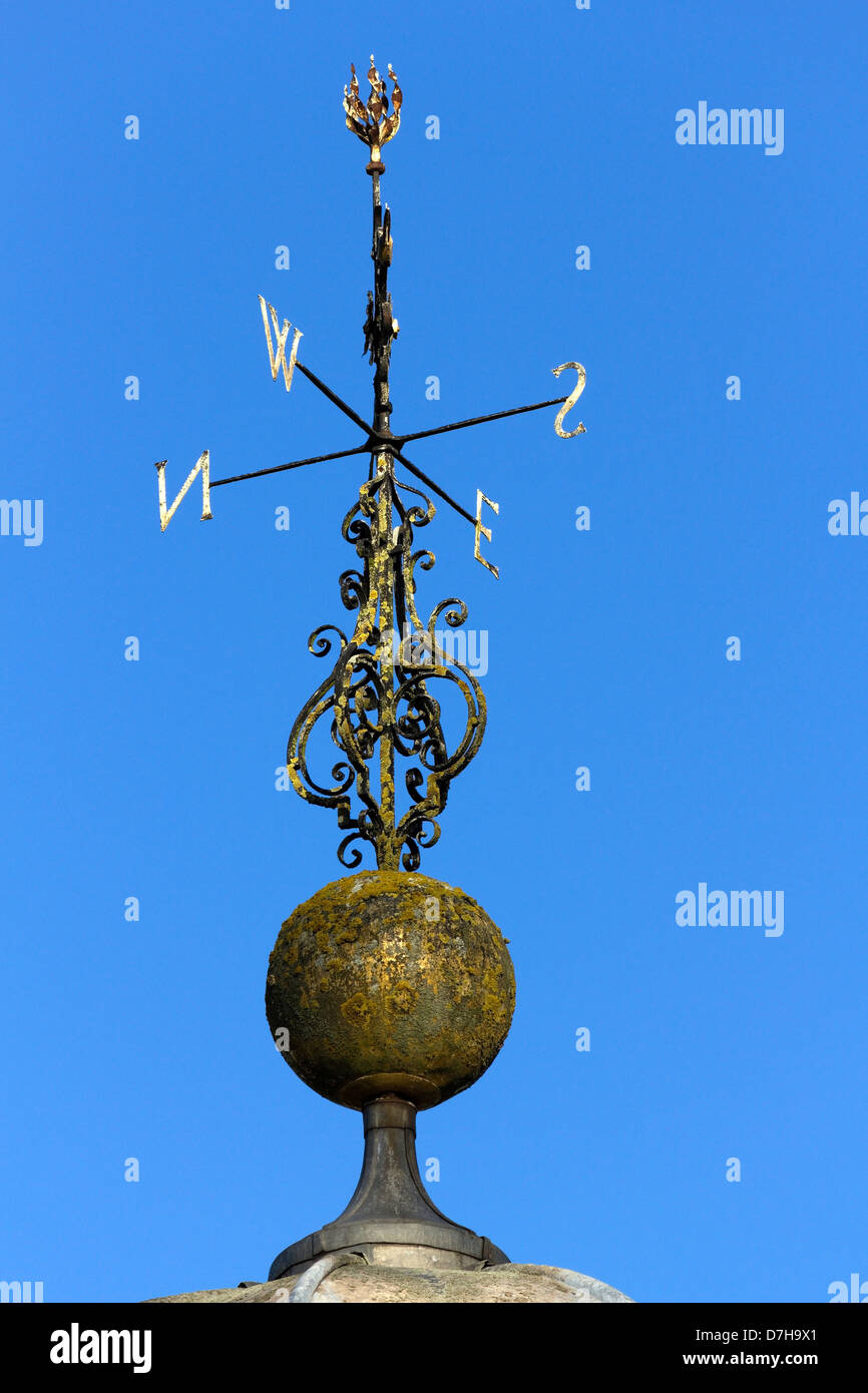 Ornate wrought iron weather vane with North South East West compass points against clear blue sky , Ticknall Derbyshire. Stock Photo