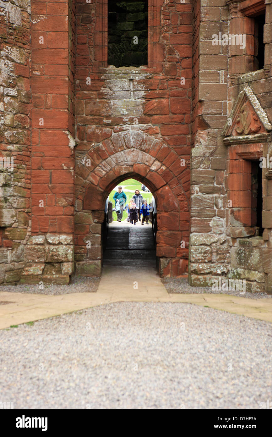 Family crossing the bridge previously the draw bridge over the moat at Caerlaverock Castle near Dunfries in Scotland Stock Photo