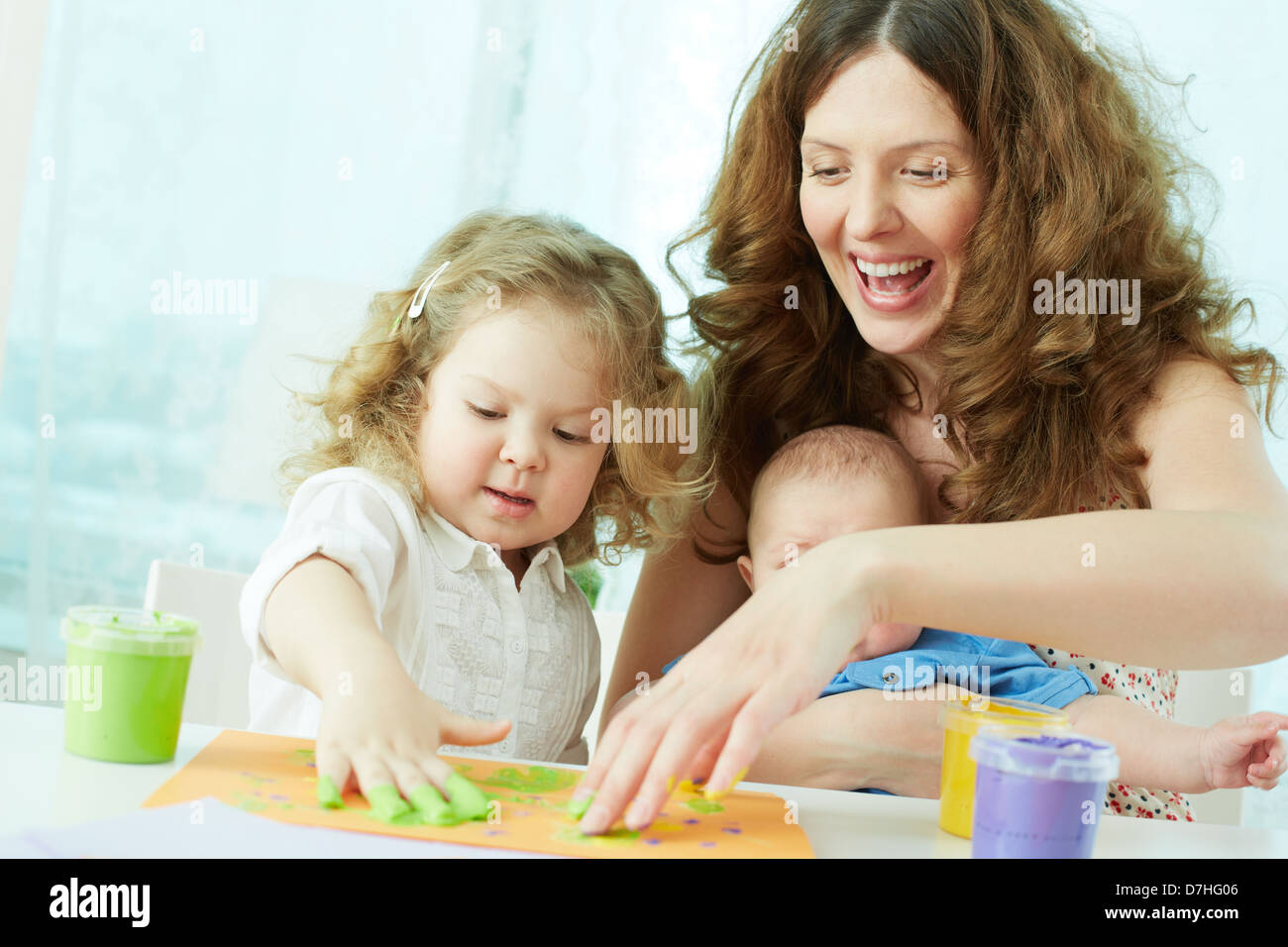 Happy mother and kids doing finger-painting Stock Photo