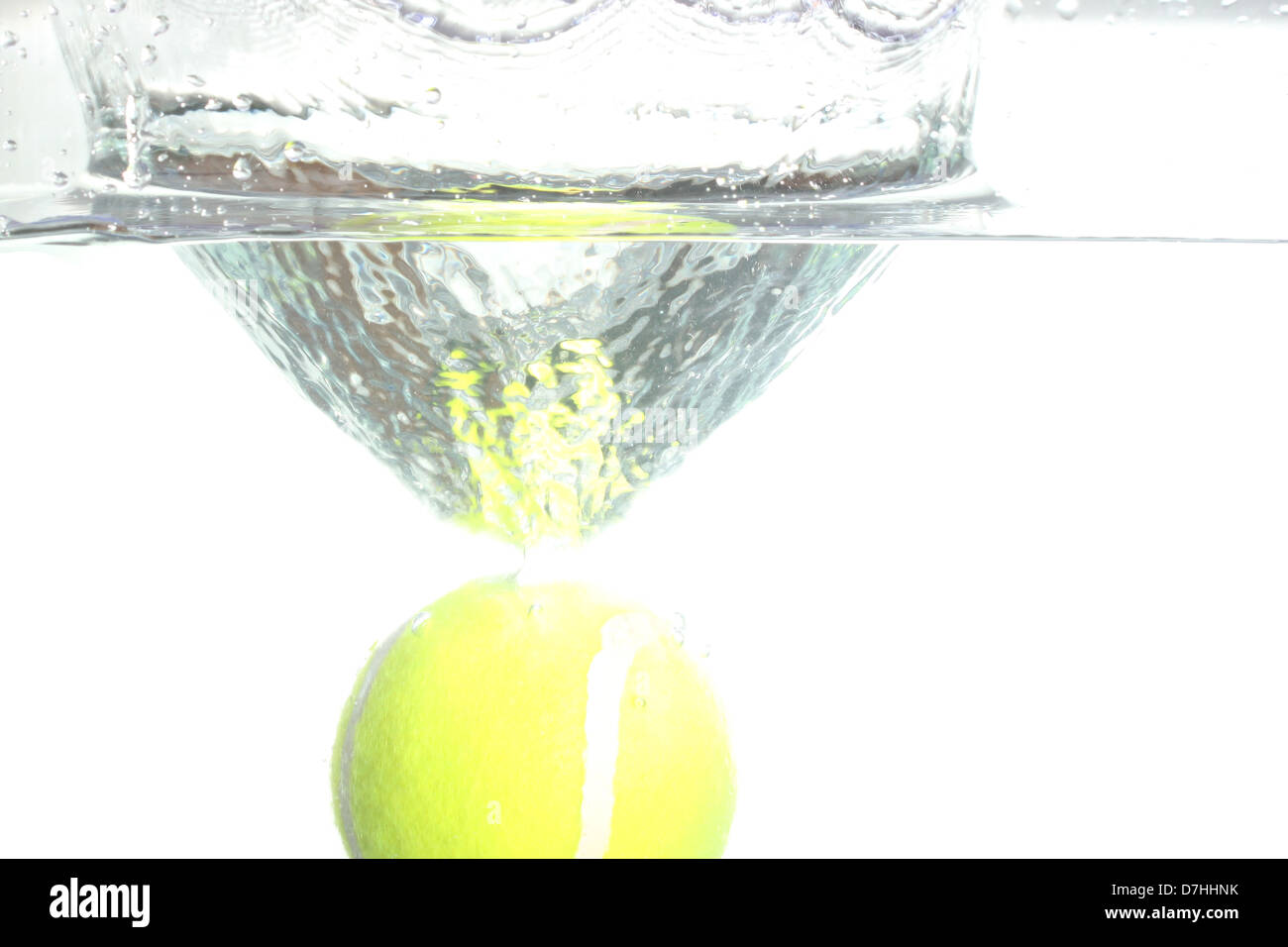 Tennis ball dropped into the water, causing spread water. Stock Photo