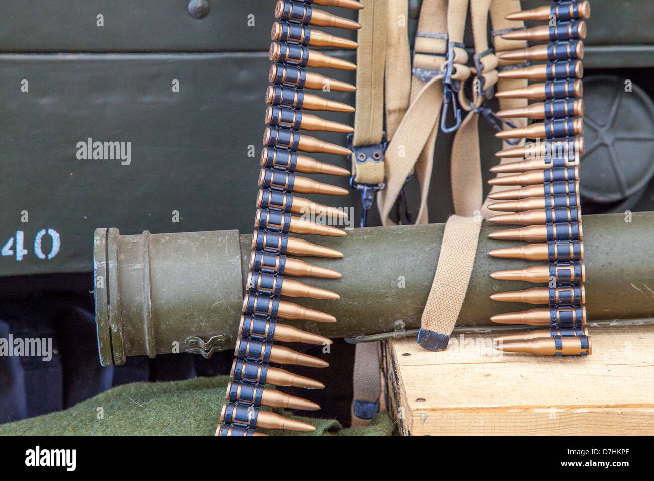 A vintage bandoleer of machine gun bullets resting over a World War II-era bazooka, representing the rugged and improvised nature of combat gear used. Stock Photo