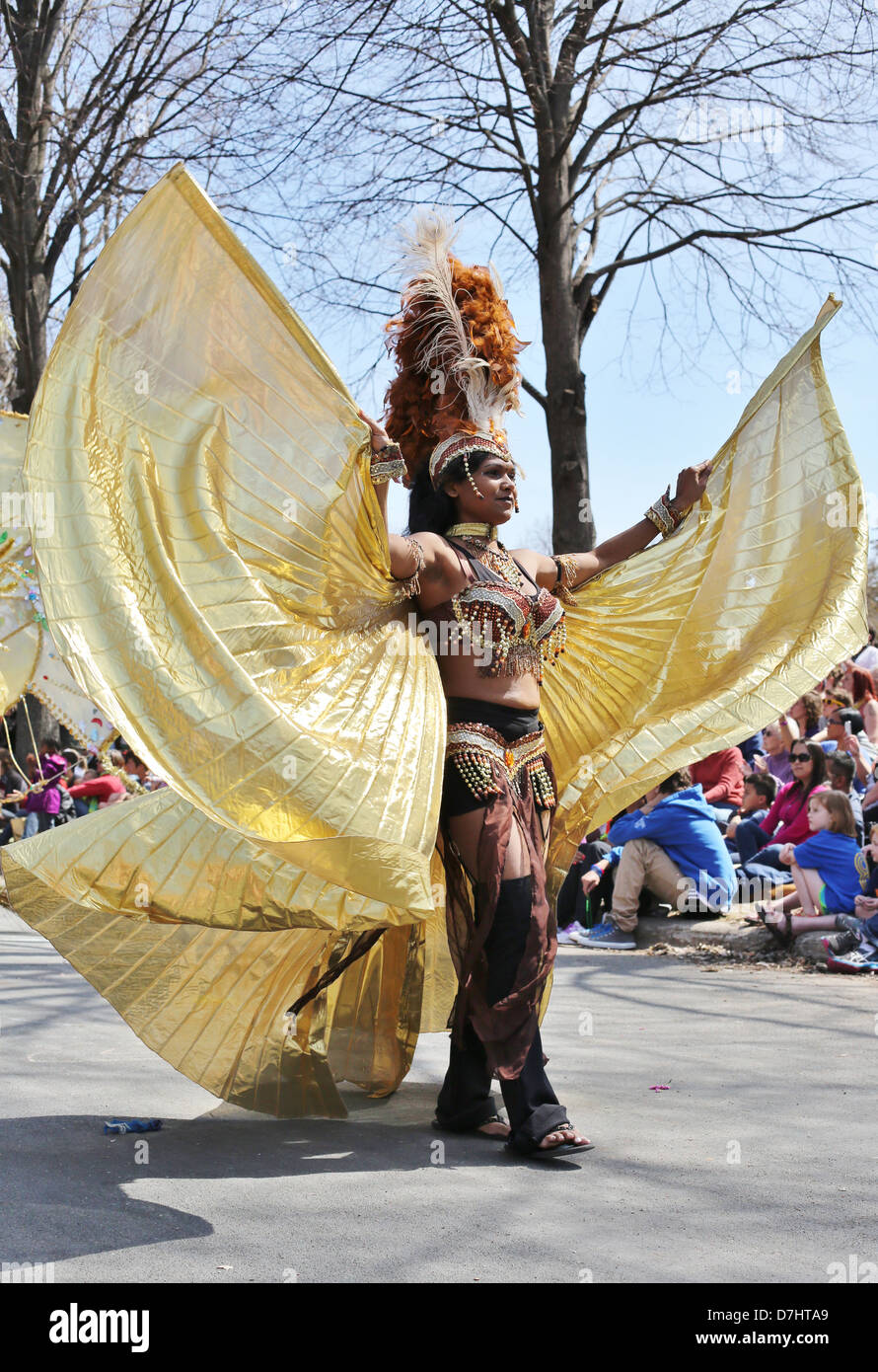 A woman in a beautiful gold costume dancing at the May Day parade in