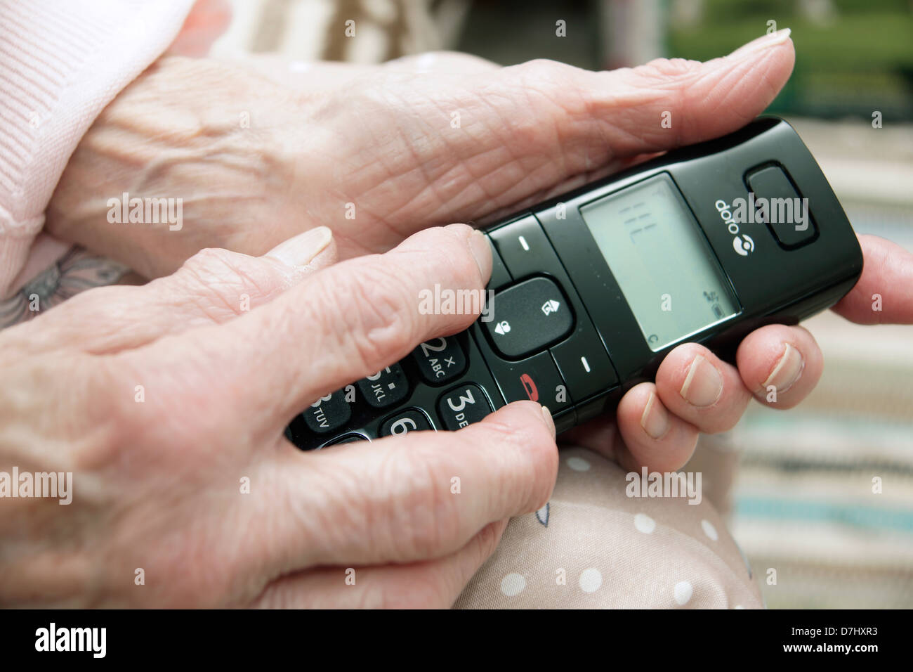 Elderly woman using a specialised big button telephone phoning the 111 non emergency medical advice helpline due to feeling ill Stock Photo