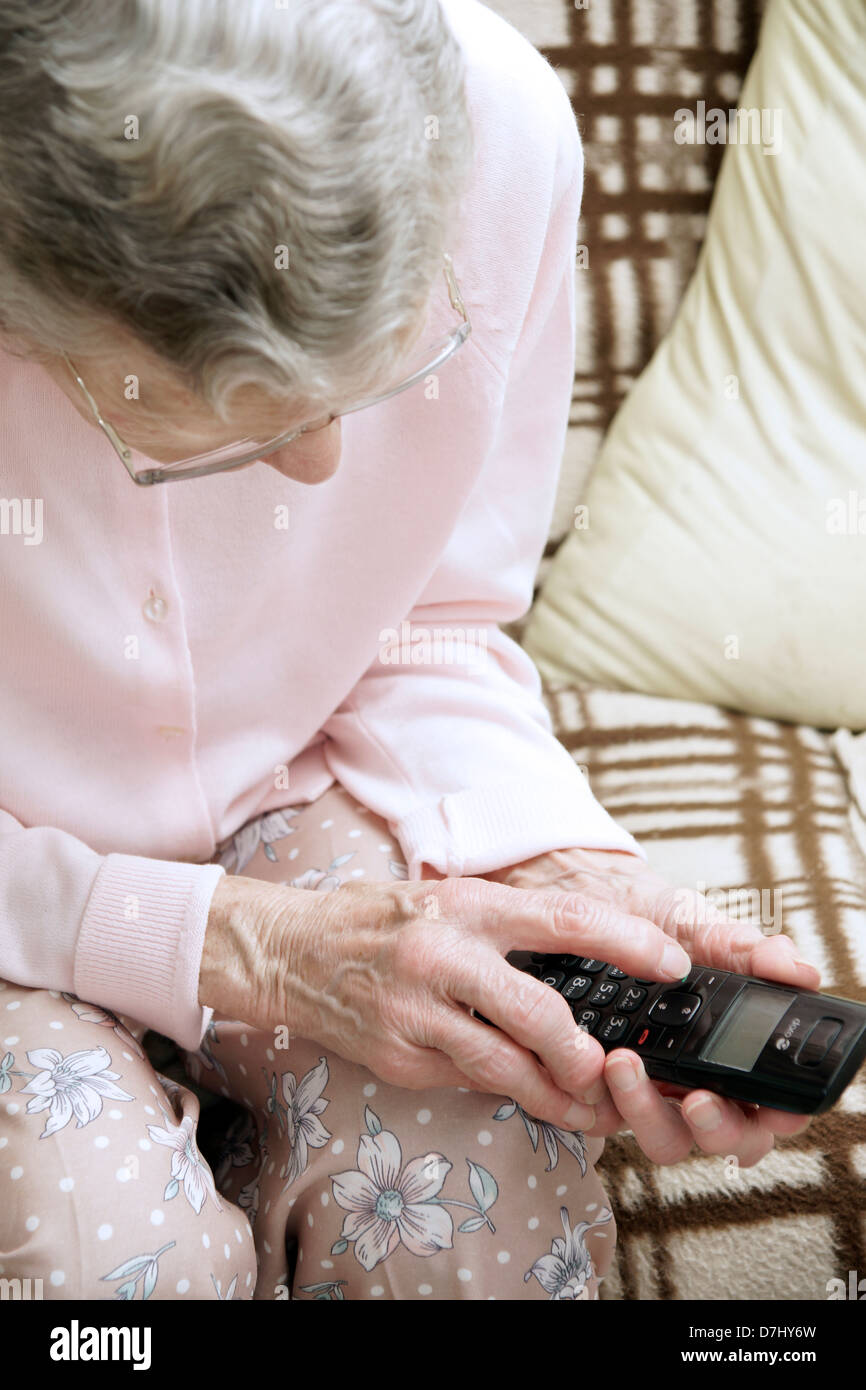 Elderly woman using a specialised big button telephone phoning the 111 non emergency medical advice helpline due to feeling ill Stock Photo