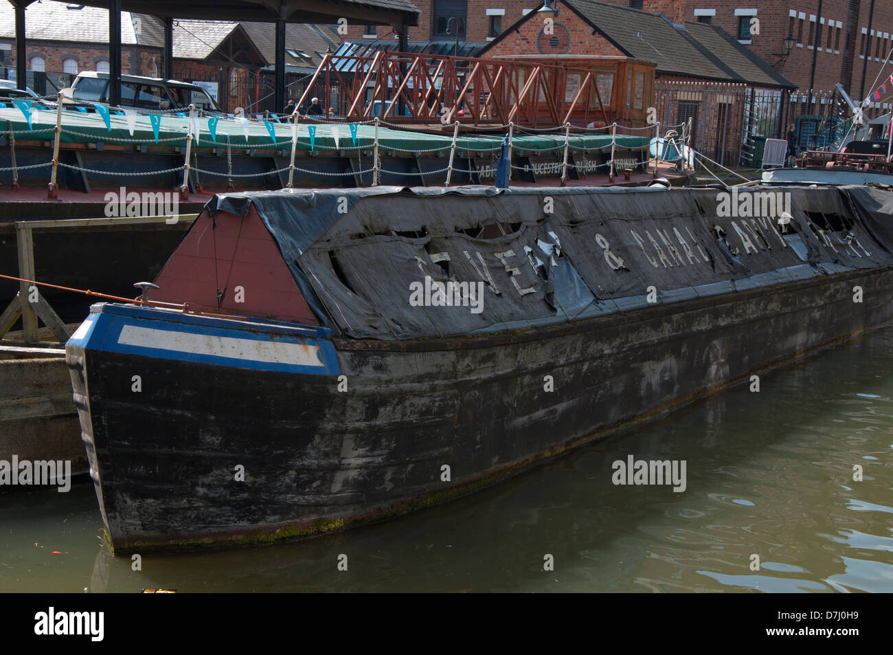 canal boat, old working boat,old cargo boat, worn, tired, berthed, tattered tarpaulins Stock Photo