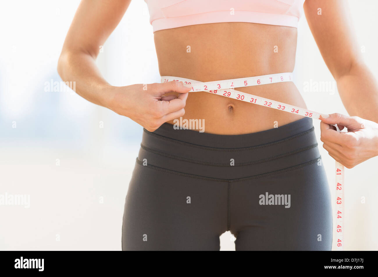 Woman holding tape measure around waist - Stock Image - F020/7701