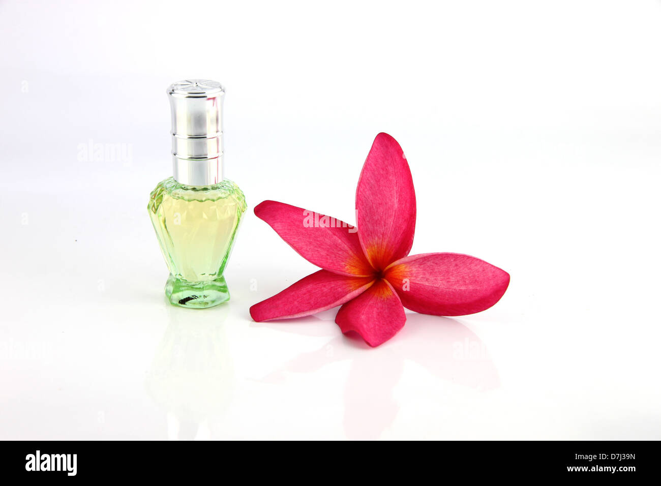 Red flowers and Green Perfume bottles on the white background. Stock Photo