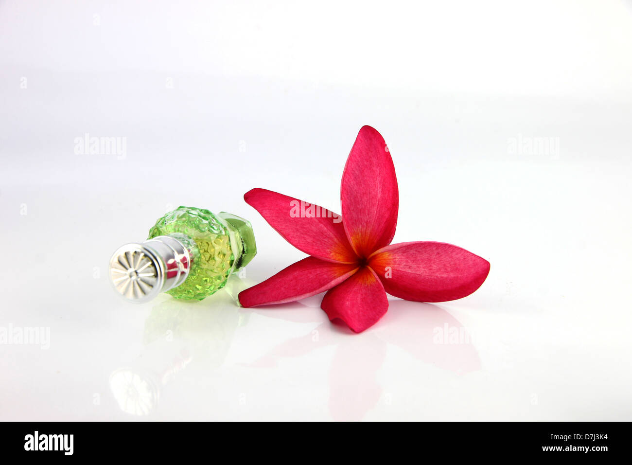 Red flowers and Green Perfume bottles on the white background. Stock Photo