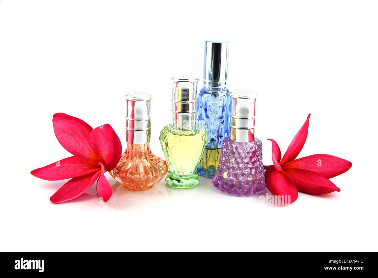 The Red flowers and Orange,Blue,Green,Violet Perfume bottles on the white background. Stock Photo