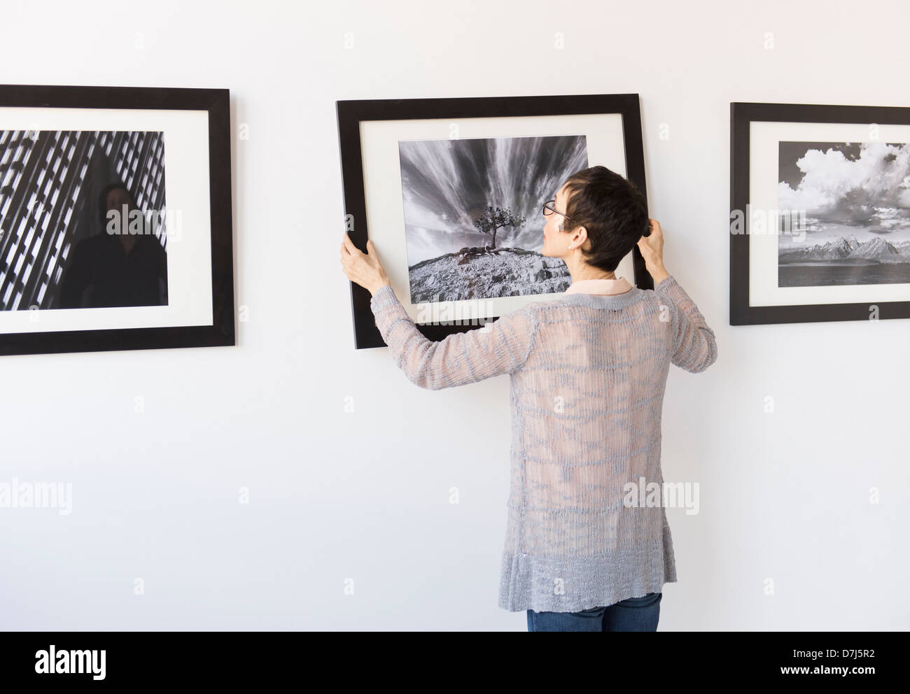 Woman hanging photographs in art gallery Stock Photo