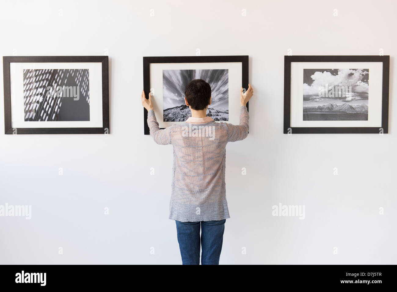 Woman hanging photographs in art gallery Stock Photo