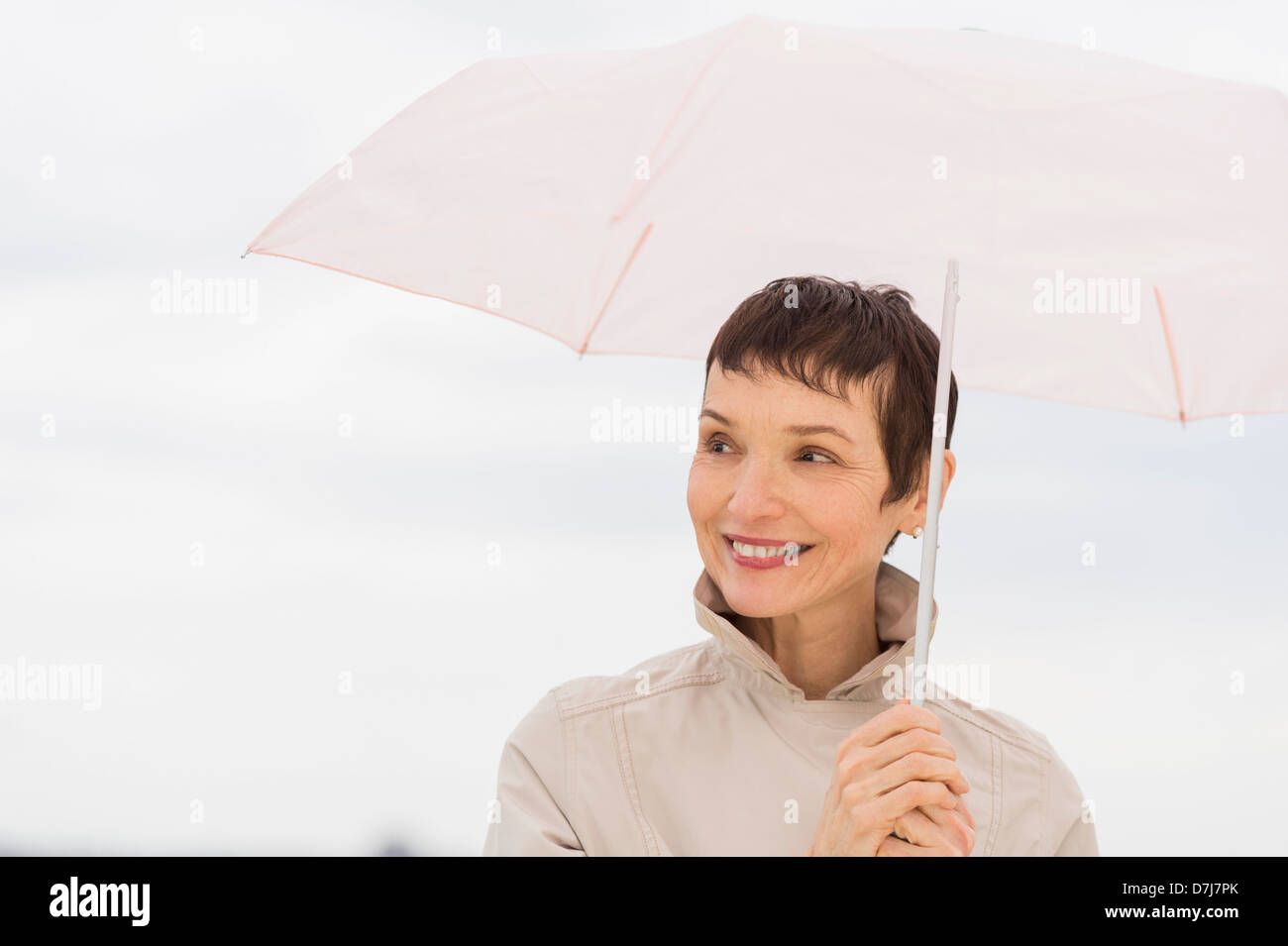 Portrait of smiling woman wearing raincoat and holding umbrella Stock Photo