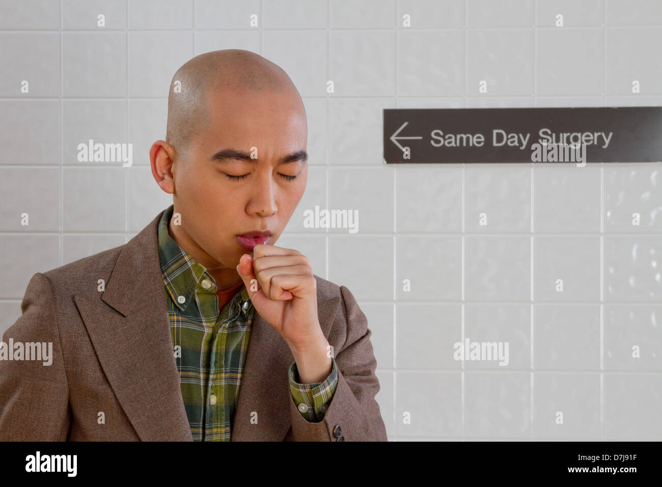 Young man coughing in hospital hallway. Stock Photo